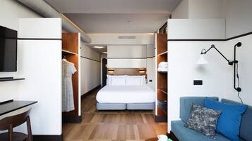 Una habitación de hotel moderna con cama, escritorio, sofá y televisor.
