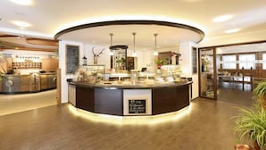 Un espace d’accueil doté d’un comptoir incurvé, d’un bureau de réception et d’une enseigne sur laquelle on peut lire : « Bienvenue à l’hôtel ».