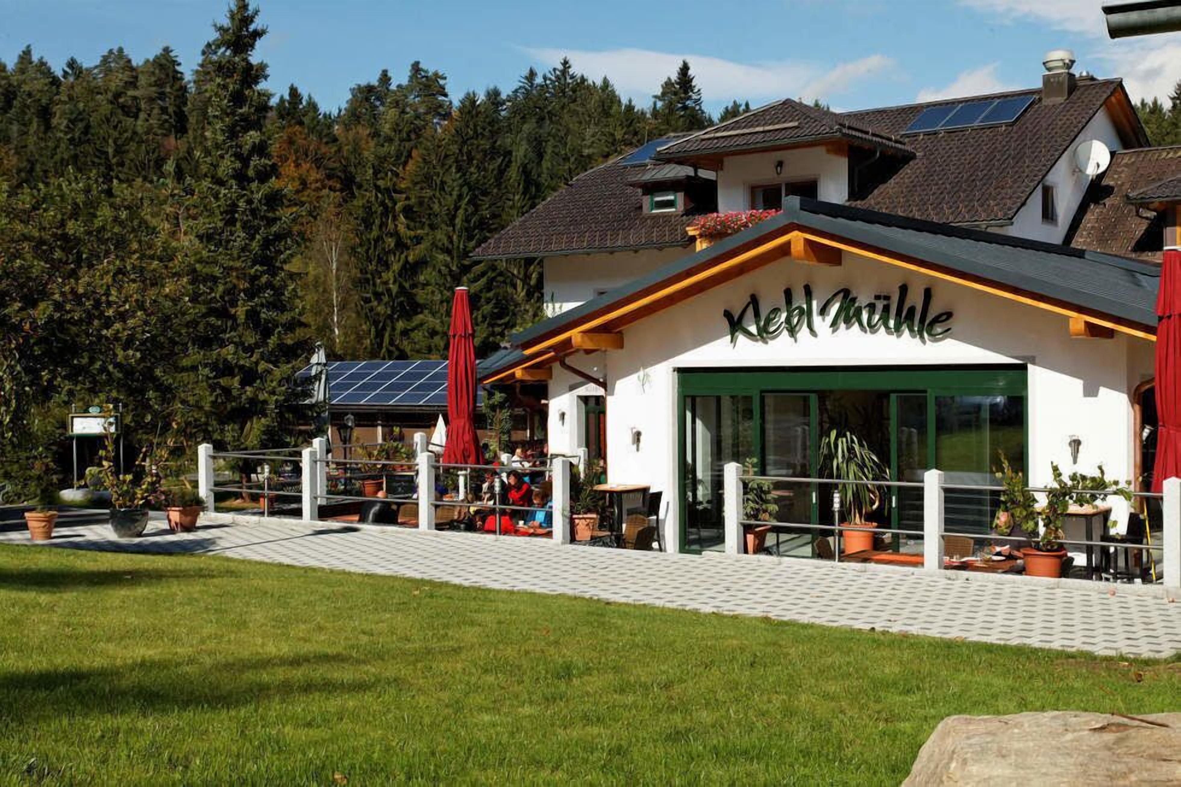 A building with a sign reading "Kleinhaus" and solar panels on the roof.