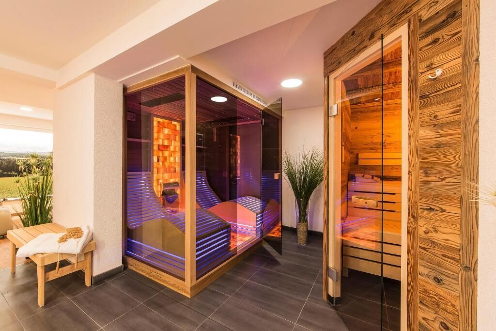 Een moderne spa ruimte met een glazen omheining, een houten bank en uitzicht op de omgeving.