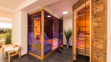 Een moderne spa ruimte met een glazen omheining, een houten bank en uitzicht op de omgeving.