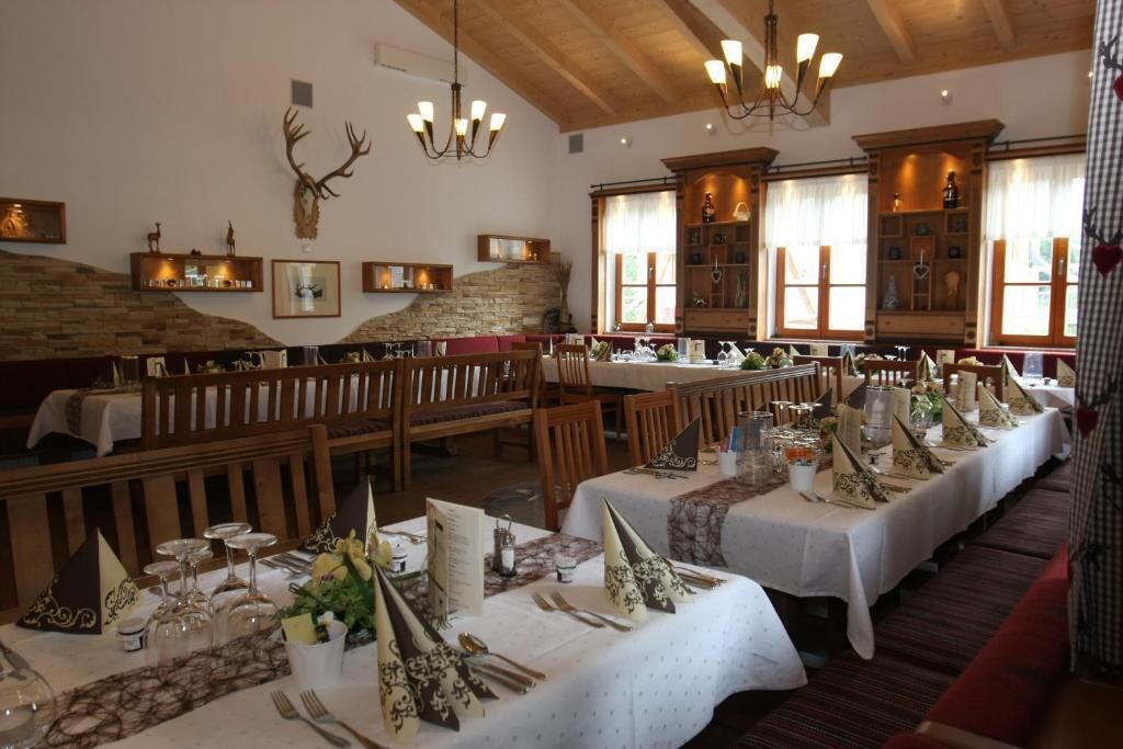 Restaurante com mesas de madeira preparadas para refeições, paredes de pedra e um candelabro.