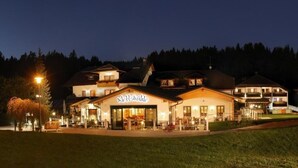 Un hôtel avec une enseigne bien visible, de nombreux étages et une façade bien éclairée la nuit.