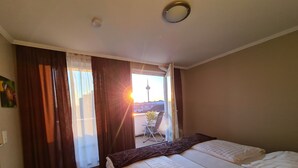 A hotel room with two beds, a balcony, and a view of the cityscape. - Cara Vita Hotel (Cologne)