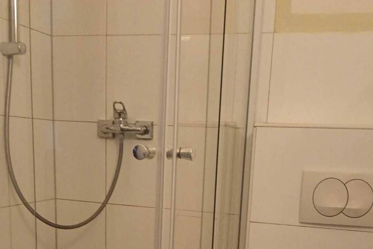 A bathroom with a glass-enclosed shower, a toilet, and a towel rack.