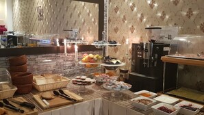 A buffet setup with various food items, a coffee machine, and a refrigerator. - Cara Vita Hotel (Cologne)