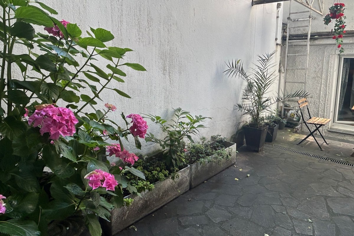 A courtyard with potted plants, a wooden bench, and a door.