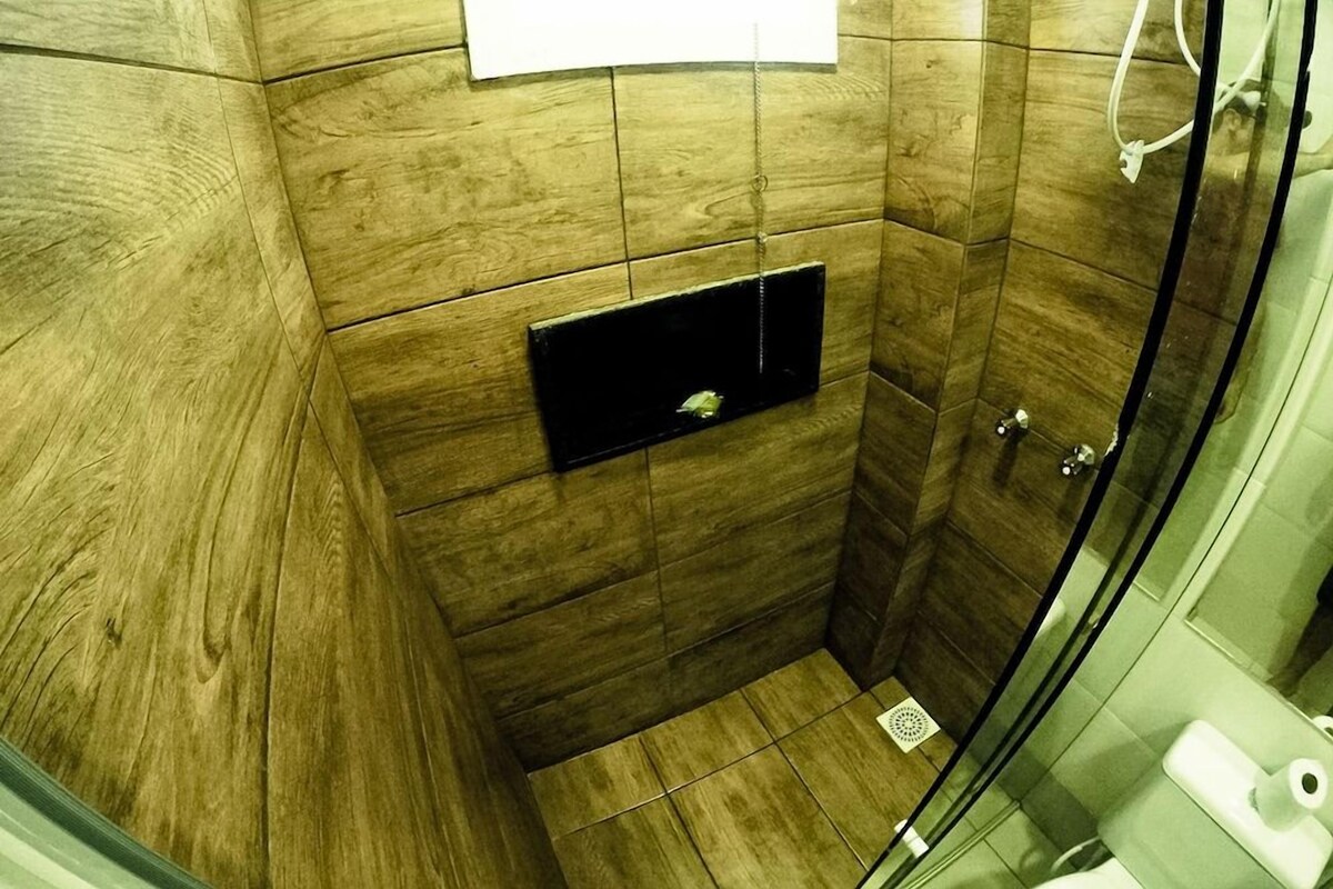 Un espace douche doté d’une porte en verre, d’une petite étagère et de toilettes.
