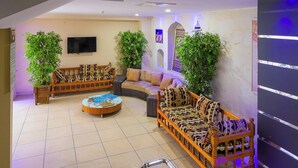 A spacious indoor area with two sofas, a coffee table, and potted plants. - Rabis Otel (Sanliurfa)