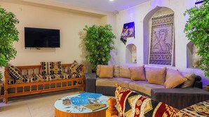 A living room with a sofa, a wooden bench, a coffee table, and a TV. - Rabis Otel (Sanliurfa)