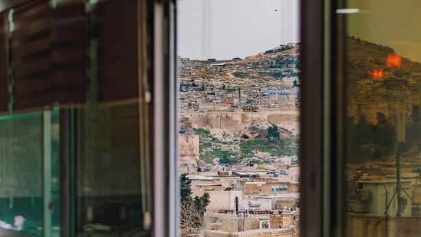 A view from a window of a building with a dining area in the foreground and a mountainous landscape in the background. - Rabis Otel (Sanliurfa)