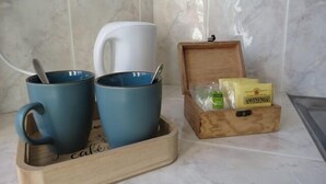 A kitchen area with two blue mugs on a wooden tray, a white mug, and a wooden box containing tea bags and a box of tea. - Cafe Restaurant Meuble de Tourisme (Saint-Germain-de-Calberte)
