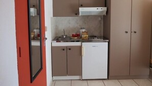A compact kitchen with a refrigerator, stove, and cabinets. - Cafe Restaurant Meuble de Tourisme (Saint-Germain-de-Calberte)