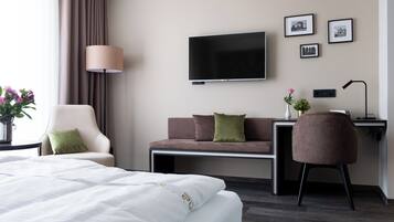 Una habitación de hotel con una cama, un sofá, un escritorio, un televisor y una lámpara.