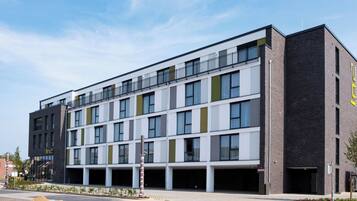 A modern multi-story building with a flat roof, large windows, and a mix of brick and white facade.