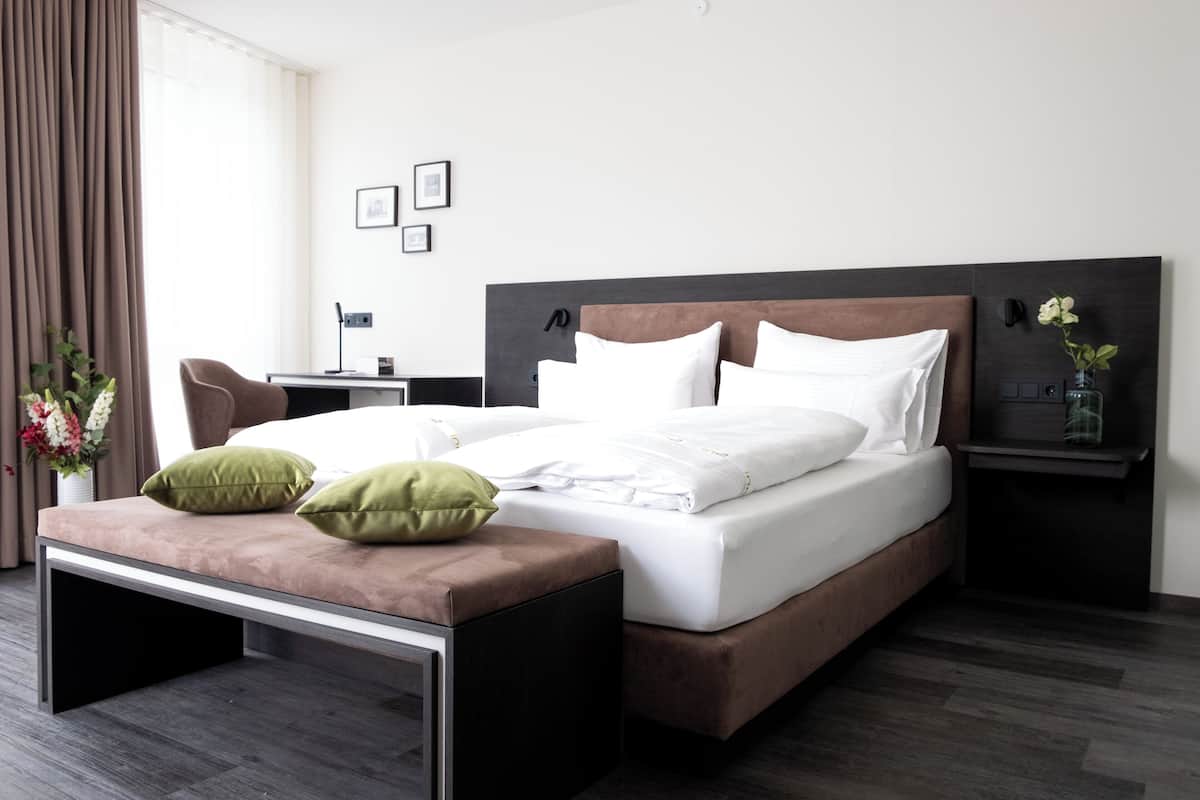 A modern hotel room with a large bed, a desk, and a chair.
