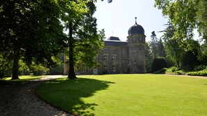A large, historic building with a prominent dome and multiple windows, surrounded by well-maintained lawns and trees. - in2 The Boardinghouse (Uebach-Palenberg)