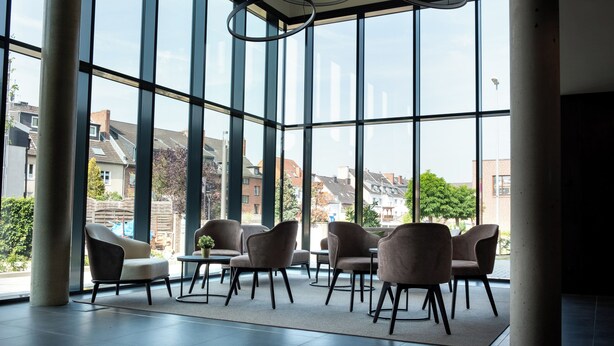 A spacious indoor area with large windows, modern chairs, and a central table. - in2 The Boardinghouse (Uebach-Palenberg)