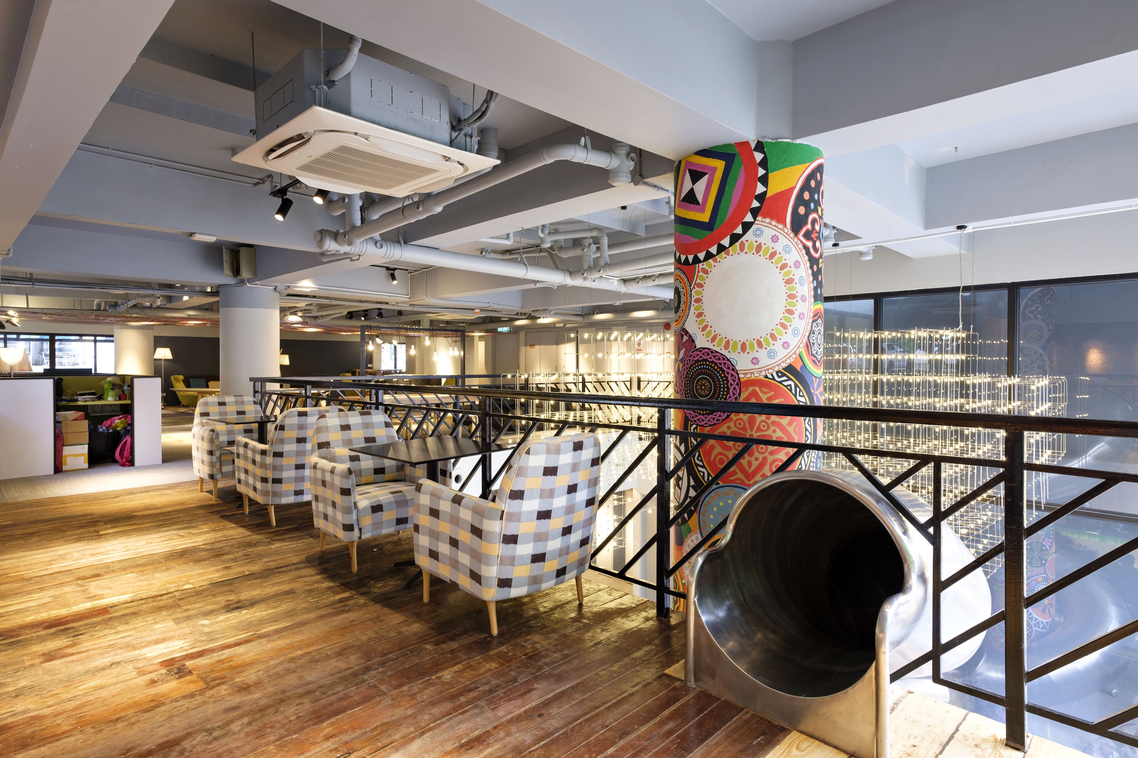 Un intérieur moderne avec des chaises à carreaux, une colonne décorative aux couleurs vives et un toboggan.