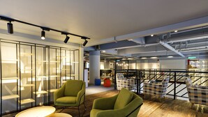 A modern interior with green armchairs, a wooden table, and a staircase with a railing. - TOOJOU Kota Kinabalu - Travel Meets Social (Kota Kinabalu)