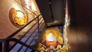A staircase with a mural featuring a cartoon character and a sun. - TOOJOU Kota Kinabalu - Travel Meets Social (Kota Kinabalu)