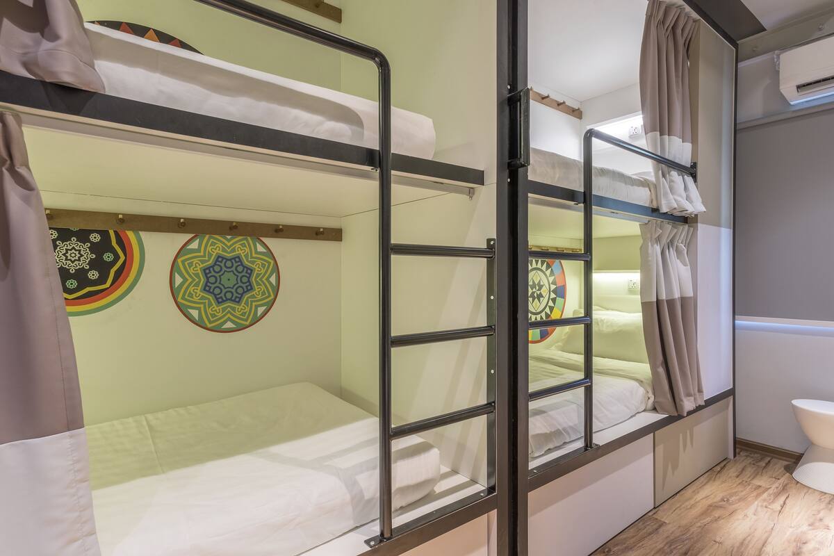 A bunk bed room with a window, a curtain, and a wall decoration.