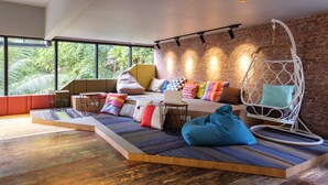 A modern living room with a sofa, a hanging chair, and a laptop on a table. - TOOJOU Kota Kinabalu - Travel Meets Social (Kota Kinabalu)