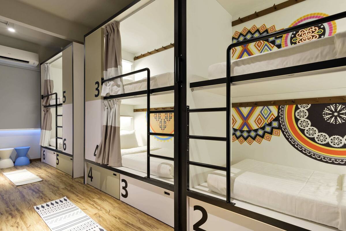 A bunk bed room with numbered compartments, a small seating area with a blue chair, and a patterned rug on the floor.