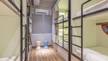 A dormitory room with bunk beds, a toilet, and a window.