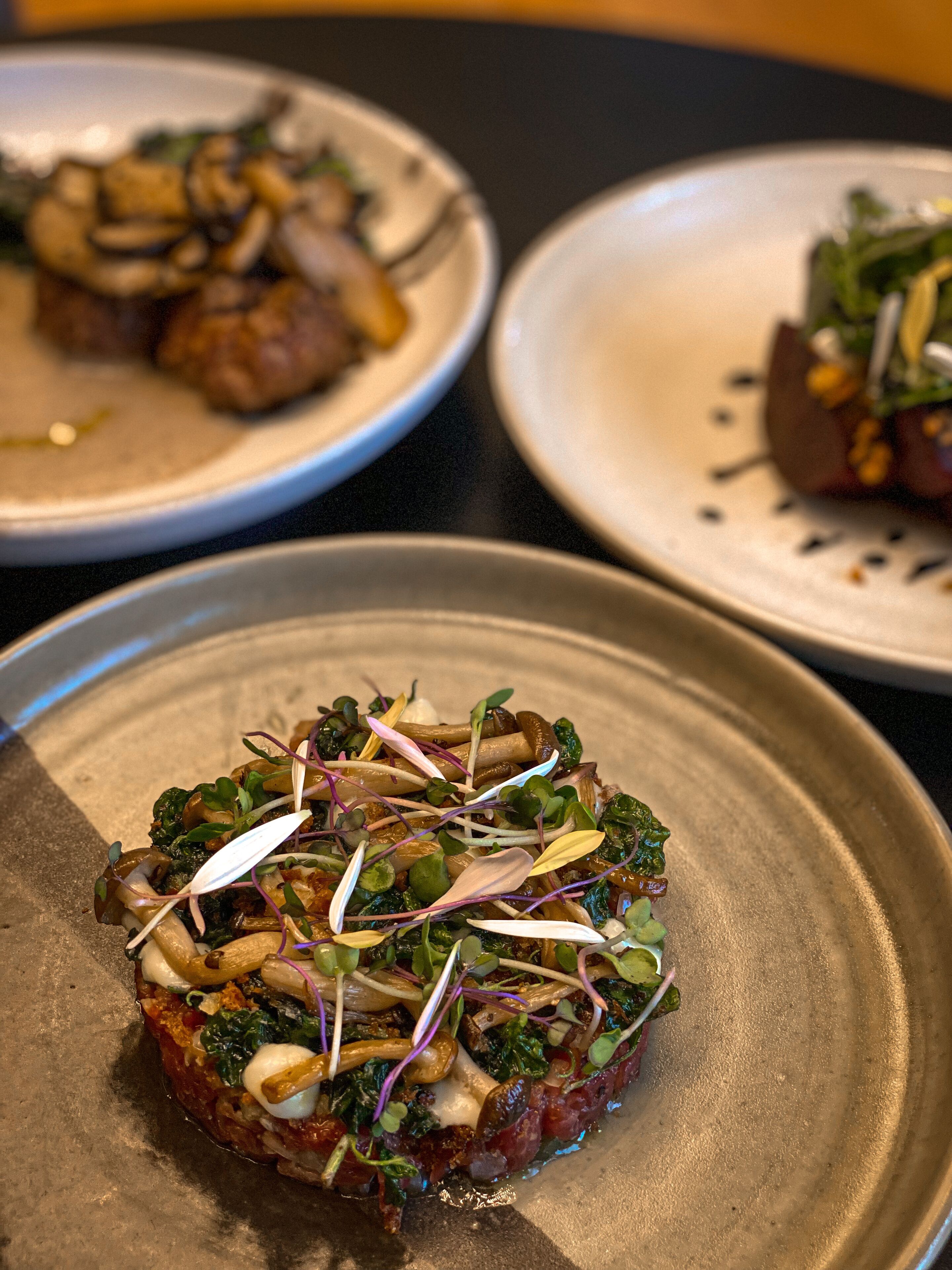 A plate of food with greens, mushrooms, and sprouts.