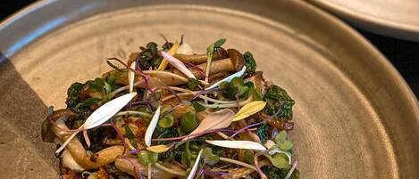 A plate of food with greens, mushrooms, and sprouts.