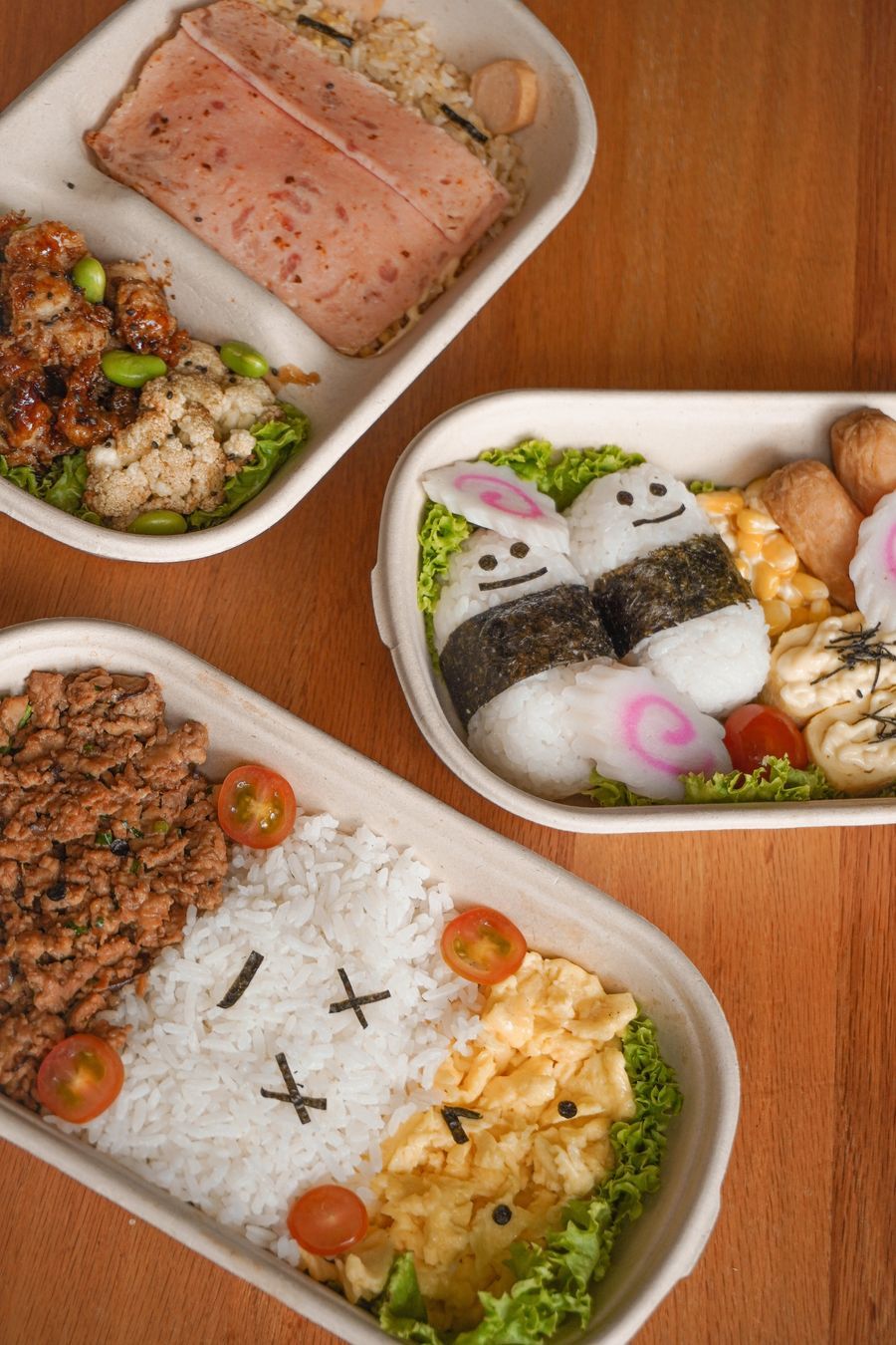 Three bento-style meal containers with various food items.