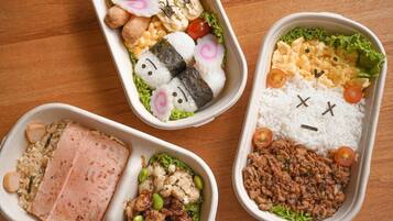 Three bento boxes with various food items.