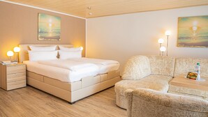 Ett hotellrum med en säng, ett sängbord, en lampa och en soffa.