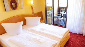 Habitación de hotel con dos camas, un balcón con mesa y sillas, y un cuadro en la pared.