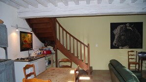 A dining area with a wooden table and chairs, a kitchen with a microwave and sink, a staircase, and a painting on the wall. - La Tour (Marcilly-la-Gueurce)