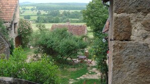 A rustic stone building with a view of a rural landscape, including trees and a distant field. - La Tour (Marcilly-la-Gueurce)