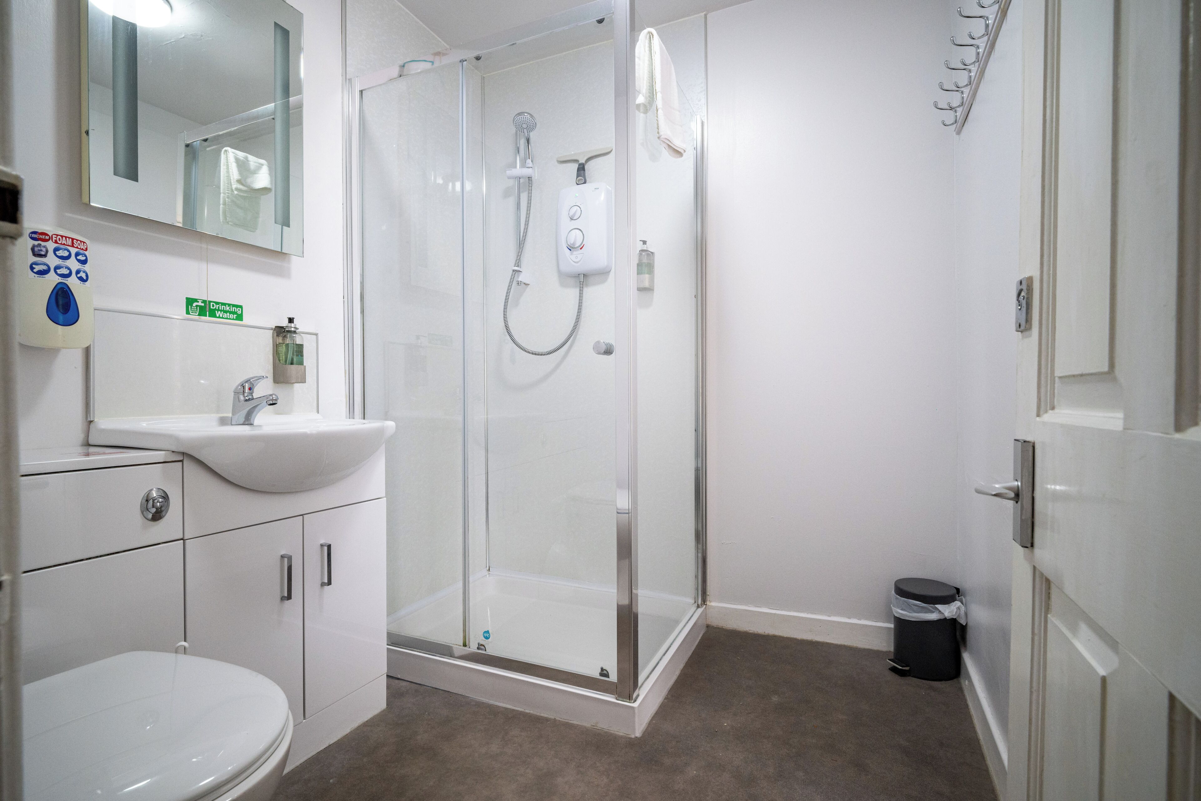 A bathroom with a toilet, sink, shower, and a glass-enclosed shower stall.
