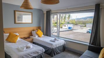 Ein Hotelzimmer mit zwei Betten, einem großen Fenster und Blick nach draußen.
