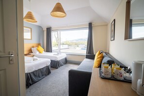 Habitación de hotel con dos camas, un sofá, espacio para café y vistas al exterior.