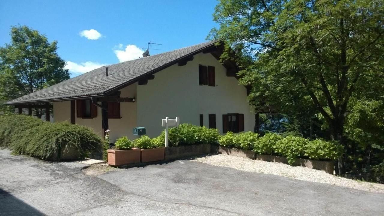 Ein zweistöckiges Haus mit Satteldach, einer Veranda und einem kleinen Garten mit Topfpflanzen.