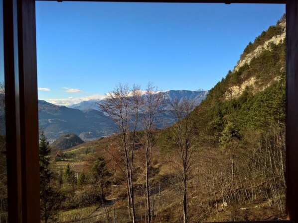 A mountainous landscape with a clear sky, trees, and distant mountains.