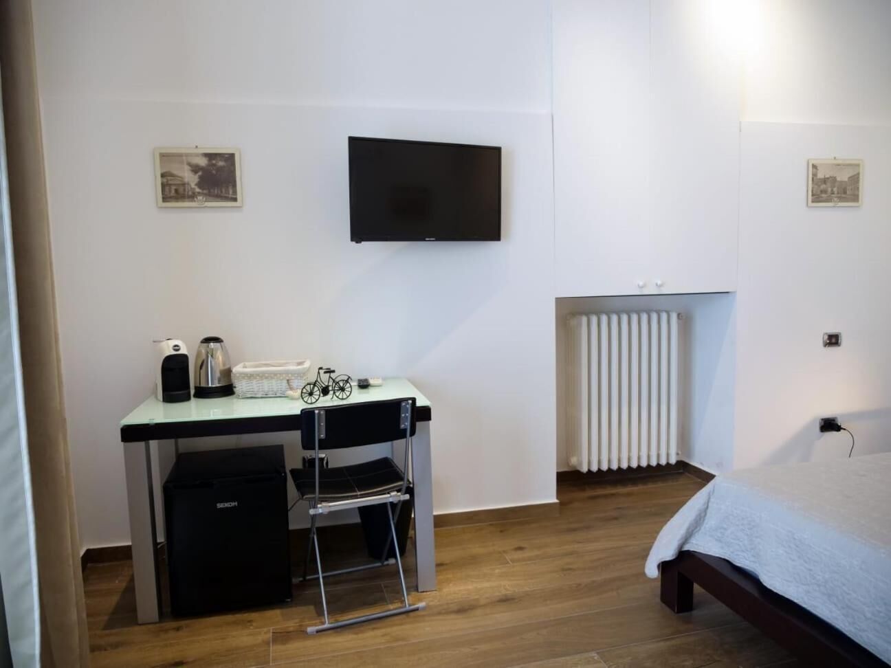 Une chambre d’hôtel comprenant un lit, un bureau avec une chaise, une télévision, un radiateur et un petit réfrigérateur.