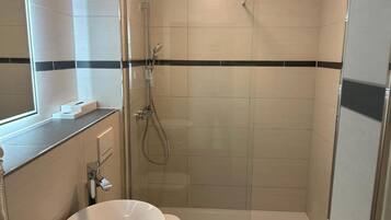 A modern bathroom with a glass-enclosed shower, a white sink, and a toilet.