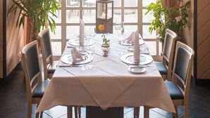 Comedor con una mesa preparada para cuatro, ventanas amplias y plantas en macetas.