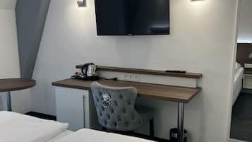 Una habitación de hotel con cama, escritorio, silla, televisor y cafetera.