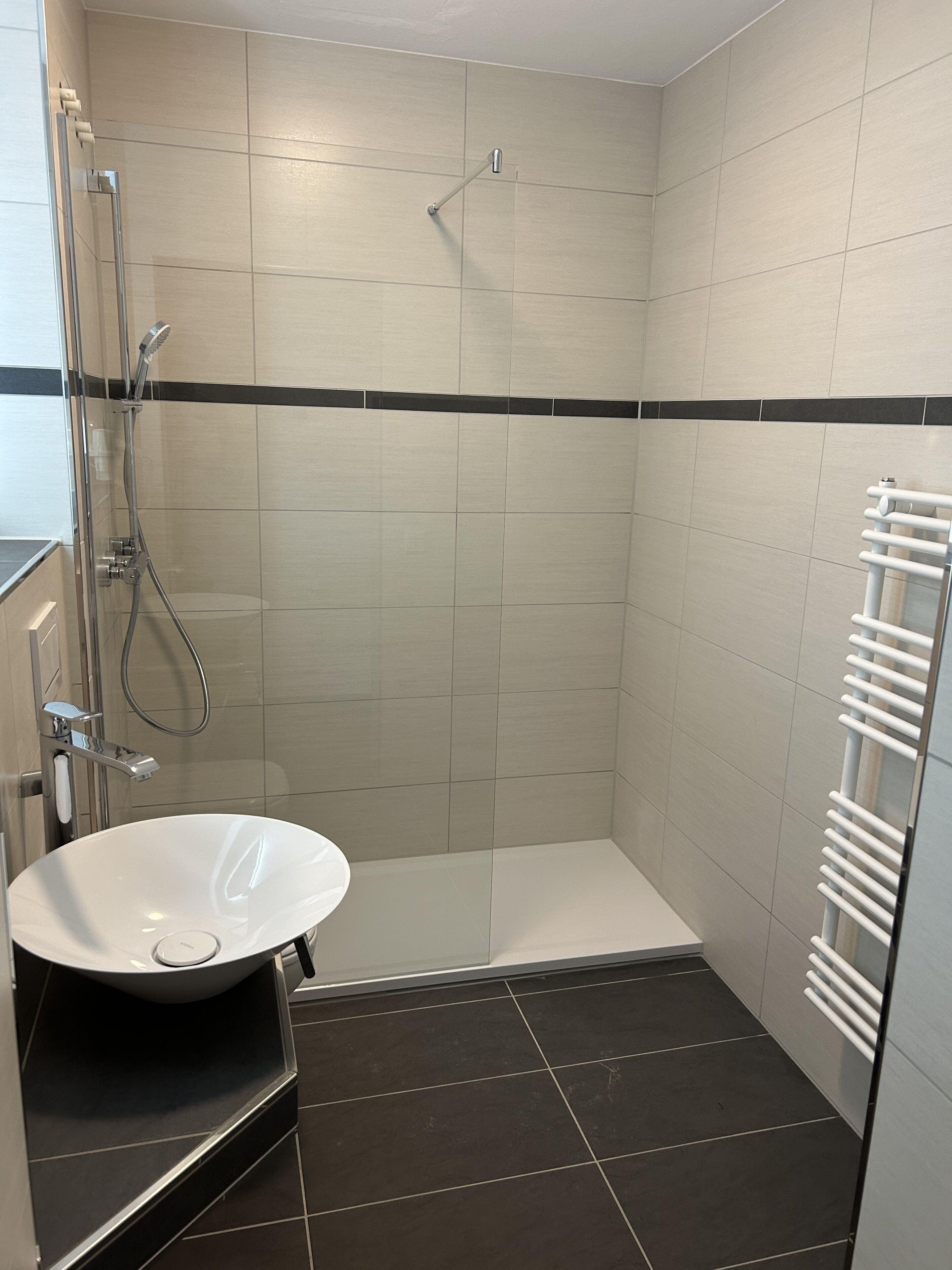 A bathroom with a white sink, a glass-enclosed shower, and a white towel rack.