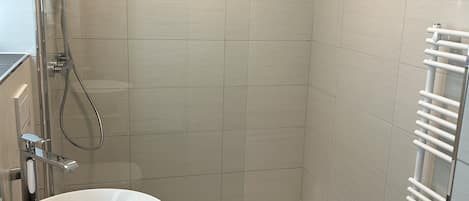 A bathroom with a white sink, a glass-enclosed shower, and a white towel rack.