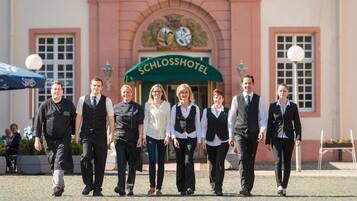 A group of people walking in front of a hotel named 'SCHLOSSHOTEL'.