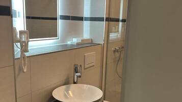 A bathroom with a white sink, a mirror, and a toilet.
